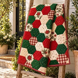 Puede incluir: Una manta acolchada con un patrón de patchwork hexagonal en rojo, verde y crema. Los paneles de tela muestran varios estampados que incluyen flores de pascua, agujas de pino y cuadros, rematados con un borde fino a cuadros rojos y blancos.