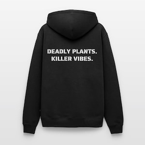 May include: A black hooded sweatshirt featuring the white text "DEADLY PLANTS. KILLER VIBES." printed on the back. The garment includes a hood, long sleeves with ribbed cuffs, and a ribbed hem, showcasing a plain black fabric construction throughout.