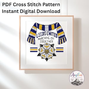 May include: A PDF cross stitch pattern featuring a blue, yellow, and white scarf draped over the text Leeds United Marching On Together, with a white rose emblem below. The design includes horizontal stripes and the Angilow Designs logo.