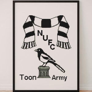May include: A framed cross-stitch pattern featuring a black and white striped scarf, a magpie perched on a stone pedestal, and the text NUFC and Toon Army. The design uses a pixelated aesthetic with a black frame and a white background.