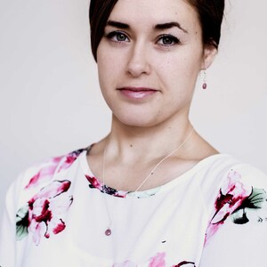 Puede incluir: Una mujer con cabello casta&ntilde;o que lleva una blusa blanca con estampado floral. Lleva un collar de plata con un colgante de piedra rosa y pendientes de plata con detalles de piedra rosa.