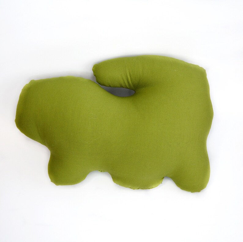 May include: A green, irregularly shaped pillow made of soft fabric. The pillow has a unique, organic shape and is perfect for adding a touch of whimsy to any room.