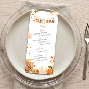 May include: A vertical rectangular menu card featuring a watercolour autumn theme with falling orange leaves and a pumpkin. The top shows a clothesline with baby items, and the text lists Starters, Main Dishes, Dessert, and Drinks with food items.