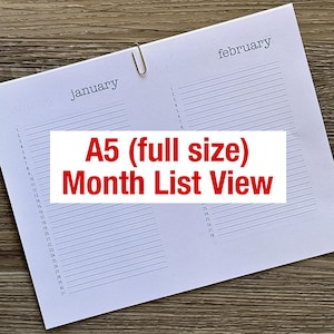May include: A white A5 paper planner insert featuring a month list view for January and February. The layout includes numbered lines from 1 to 31 for January and 1 to 28 for February. A gold metal paper clip secures the top center of the pages.