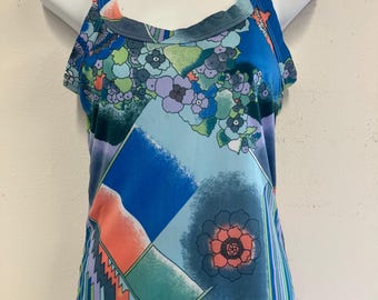 May include: A sleeveless top with a vibrant floral pattern in shades of blue, green, and purple. The top features a scoop neckline and a colorful geometric design with orange and red accents. The fabric appears to be lightweight.