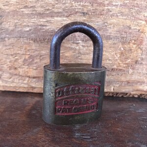 May include: A vintage brass padlock with a red inscription that reads "Dexter Reg'd Pat Off'd 181".