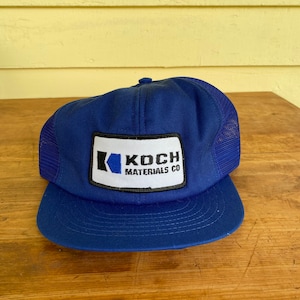 May include: A blue trucker hat with a white patch that says "Koch Materials Co."