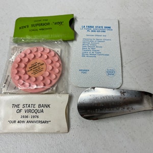 May include: A collection of vintage promotional items including a pink plastic coin with the text "Northern Wis. Co-op Tobacco Pool", a green card with the text "Ken's Superior "400" Toman Wisconsin", a white card with the text "La Farge State Bank", and a silver shoe horn with the text "Benners Family Shoe Hales Corners Wis."