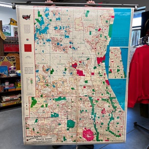 May include: A vintage map of the North Shore of Lake County, Illinois, showing the different towns and cities in the area. The map is printed on a large sheet of paper and is rolled up on a metal rod. The map is in good condition and has a vintage look.