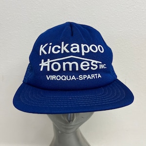 May include: A blue and white trucker hat with the text "Kickapoo Homes Inc. Viroqua-Sparta" embroidered on the front.