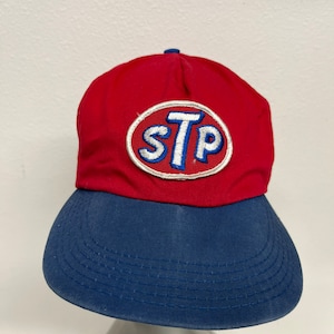 May include: A red and blue baseball cap with a white circle and the text "STP" in blue letters.
