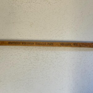 May include: A wooden ruler with the text "NORTHERN WISCONSIN TOBACCO POOL - VIROQUA, WIS." printed on it.