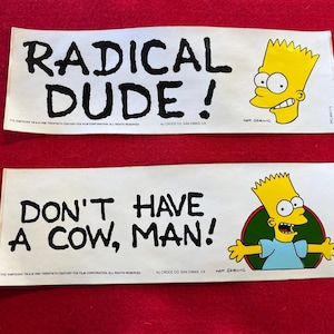 May include: Two rectangular stickers with text and cartoon images. The top sticker reads "RADICAL DUDE!" with a yellow cartoon character. The bottom sticker says "DON'T HAVE A COW, MAN!" with a cartoon character.