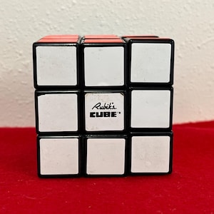 May include: A black and white Rubik's Cube with the text "Rubik's CUBE" on the center face.