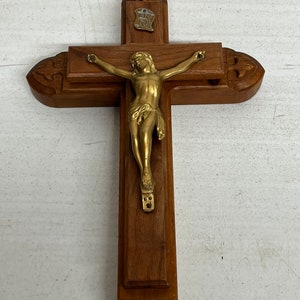May include: A wooden crucifix with a gold-toned Jesus figure. The crucifix has a small plaque with the inscription "INRI" on the top.