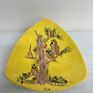 May include: A yellow triangular ceramic dish with a hand-painted design of three owls perched on a tree branch with red berries. The dish is signed "Ruth" in the bottom right corner.