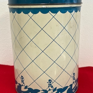 May include: A vintage blue and white tin container with a diamond pattern and a border of stylized birds and people.