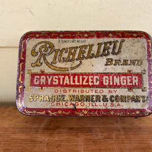 May include: A vintage tin box for Richelieu brand crystallized ginger. The box is red, gold, and white with ornate lettering and a decorative border. It reads "8 ounces net weight", "Richelieu Brand", "Crystallized Ginger", "Distributed by Sprague Warner & Company", and "Chicago, Ill. U.S.A."