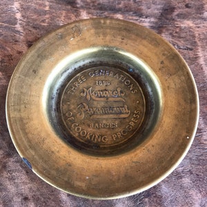 May include: A brass plate with a circular design featuring the text "Three Generations 1896 Monarch Paymont Ranges of Cooking Progress".