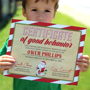May include: A red and white striped certificate with the text "CERTIFICATE of good behavior" and "OWEN PHILLIPS" awarded on December 24, 2019. The certificate is signed by Santa Claus and Elf Ernest.
