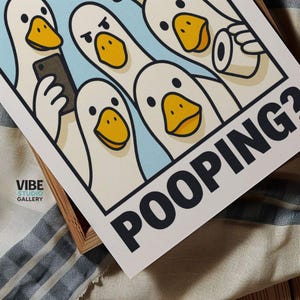 May include: A print featuring cartoon ducks with yellow beaks and black eyes. One duck holds a phone, another a roll of toilet paper. The word "POOPING?" is printed in bold black letters.