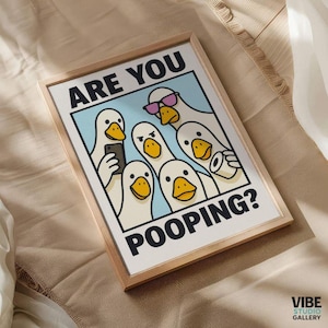 May include: Framed art print featuring a cartoon illustration of several white ducks with yellow beaks. The ducks are depicted in various poses, with one wearing sunglasses and another holding a phone. The text "ARE YOU POOPING?" is displayed in bold letters.