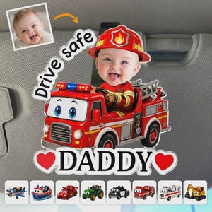 May include: A personalized car visor accessory featuring a cartoon baby in a firefighter's uniform driving a red fire truck. The text "Drive safe DADDY" is displayed. Additional vehicle designs are shown below.