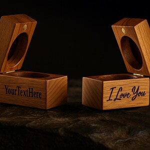 May include: Two open wooden ring boxes with a hinged lid and a circular opening. One box has "YourTextHere" engraved, the other says "I Love You". The boxes are made of light brown wood.