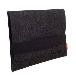 May include: A dark grey felt sleeve with a black band closure. The sleeve has a flap closure and a small orange tag on the side. The felt material has a textured appearance.