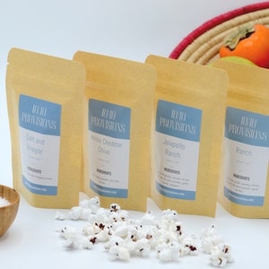 May include: Four kraft paper pouches of gourmet popcorn seasonings, labeled Salt and Vinegar, White Cheddar Chive, Jalapeño Ranch, and Ranch. The brand name is 10/10 Provisions. A small wooden bowl of salt and a pile of popcorn are in the foreground.