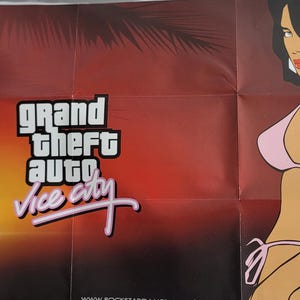 May include: A folded poster for the video game Grand Theft Auto: Vice City. The poster features the game's logo and a stylized illustration of a woman in a pink bikini. The background transitions from orange to dark red.
