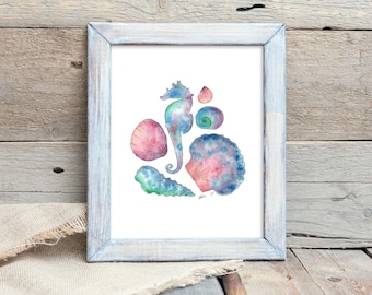 May include: Watercolor print of various seashells and a seahorse in shades of blue, pink, and green. The artwork is framed in a distressed white wooden frame. The image is displayed on a wooden surface with a linen cloth.