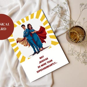 May include: A greeting card with a superhero theme. The card features a couple in superhero attire with a red and gold sunburst design. Text on the card reads "May Jehovah do more than superabundantly..." A red circle with the words "PHYSICAL CARD" is in the upper left.