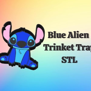 May include: A blue alien trinket tray with the text "Blue Alien Trinket Tray STL". The tray features a cartoon alien character with large ears and eyes. The background is a gradient of pink, yellow, and blue.