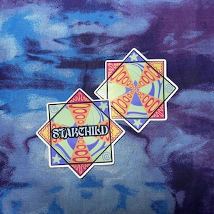 May include: Two square stickers with star-shaped points featuring a colorful geometric pattern of light green, purple, and orange. One sticker displays the word STARCHILD in a bold, dark font across the center, while the other shows the same pattern.