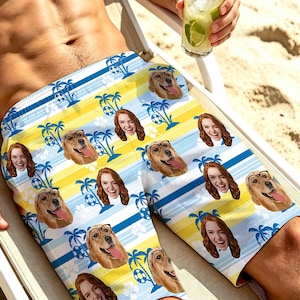 May include: Swim trunks featuring a repeating pattern of blue palm trees, white hibiscus flowers, and alternating yellow and light blue stripes. The design includes custom photo prints of a person with red hair and a golden retriever wearing glasses.