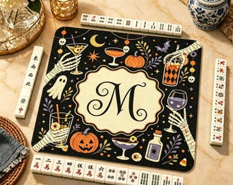 Può includere: Un tappetino da gioco quadrato con una cornice smerlata color crema al centro contenente una grande lettera M nera. Lo sfondo nero è decorato con mani scheletriche che reggono vari cocktail, zucche, fantasmi, pipistrelli e stelle.