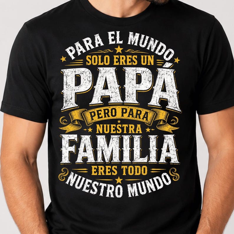 May include: A black short-sleeved t-shirt featuring white and yellow distressed-style text that reads: PARA EL MUNDO SOLO ERES UN PAP&Aacute; PERO PARA NUESTRA FAMILIA ERES TODO NUESTRO MUNDO, accented with small stars and decorative ribbon graphics.
