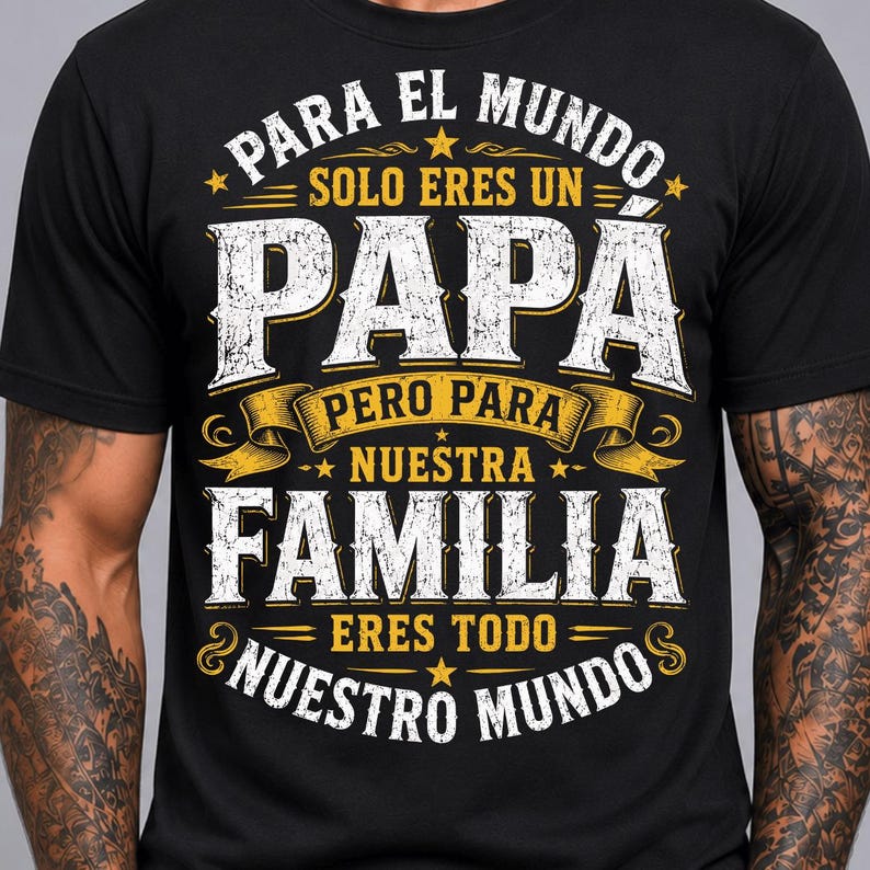 May include: A black short-sleeved t-shirt featuring white and yellow distressed text that reads: PARA EL MUNDO SOLO ERES UN PAPA PERO PARA NUESTRA FAMILIA ERES TODO NUESTRO MUNDO, accented with decorative yellow banners and small stars.