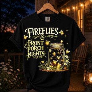 May include: A black short-sleeve t-shirt featuring a graphic of a glass mason jar filled with glowing yellow fireflies. The text "FIREFLIES & FRONT PORCH NIGHTS" is printed in yellow above the jar, surrounded by small fireflies and white daisies.