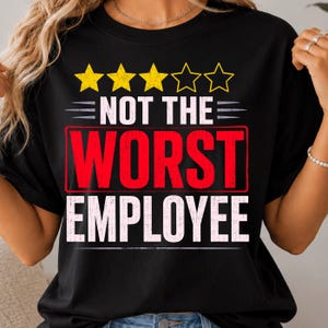 May include: A black t-shirt featuring a graphic design with three yellow stars above the white text NOT THE, followed by the word WORST in large red letters inside a red rectangular outline, and the word EMPLOYEE in white text below.