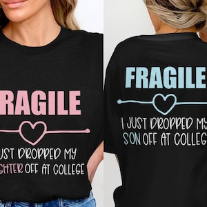 May include: Black t-shirt with the word "FRAGILE" in pink, a heart, and the text "I JUST DROPPED MY DAUGHTER OFF AT COLLEGE." The back of the shirt has the same design, but the text reads "I JUST DROPPED MY SON OFF AT COLLEGE."