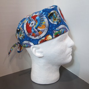 May include: Blue surgical scrub hat with a colorful dragon print. The hat has a tie at the back.
