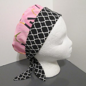 May include: A pink and black scrub hat with a geometric pattern. The hat has a tie that can be tied at the back of the head.
