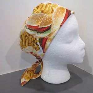 May include: A white scrub hat with a tie, featuring a print of hamburgers and french fries.