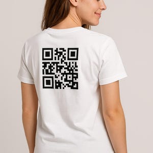 May include: A white t-shirt featuring a large black QR code on the back. The top has short sleeves and a round neck. The person is wearing black trousers.