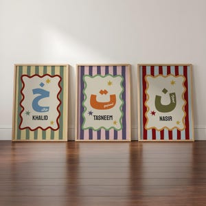 May include: Three framed wall art prints featuring Arabic letters and names. The left print has a blue letter on a striped background, the centre has an orange letter on a purple striped background, and the right has a green letter on a red striped background.