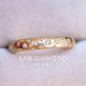 May include: A gold-colored ring with a star pattern and small, clear stones. The ring is inside a light pink jewelry box. The text "LAB DIAMOND JEWEL" is printed on the box.