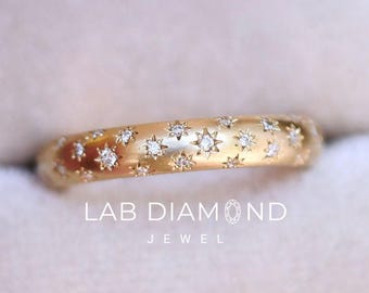 May include: A gold band ring featuring multiple small star-shaped settings, each containing a tiny embedded diamond. The ring is presented in a light-colored velvet box. The text LAB DIAMOND JEWEL is printed in white on the surface of the ring box.