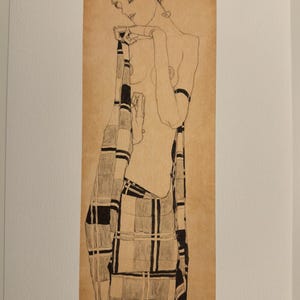 Könnte beinhalten: Schwarz-Weiß-Strichzeichnung einer nackten Figur, die in einem karierten Stoff drapiert ist. Das Kunstwerk befindet sich auf einem beigefarbenen Hintergrund, mit der Signatur des Künstlers und der Editionsnummer. Die Figur befindet sich in einer kontemplativen Pose.